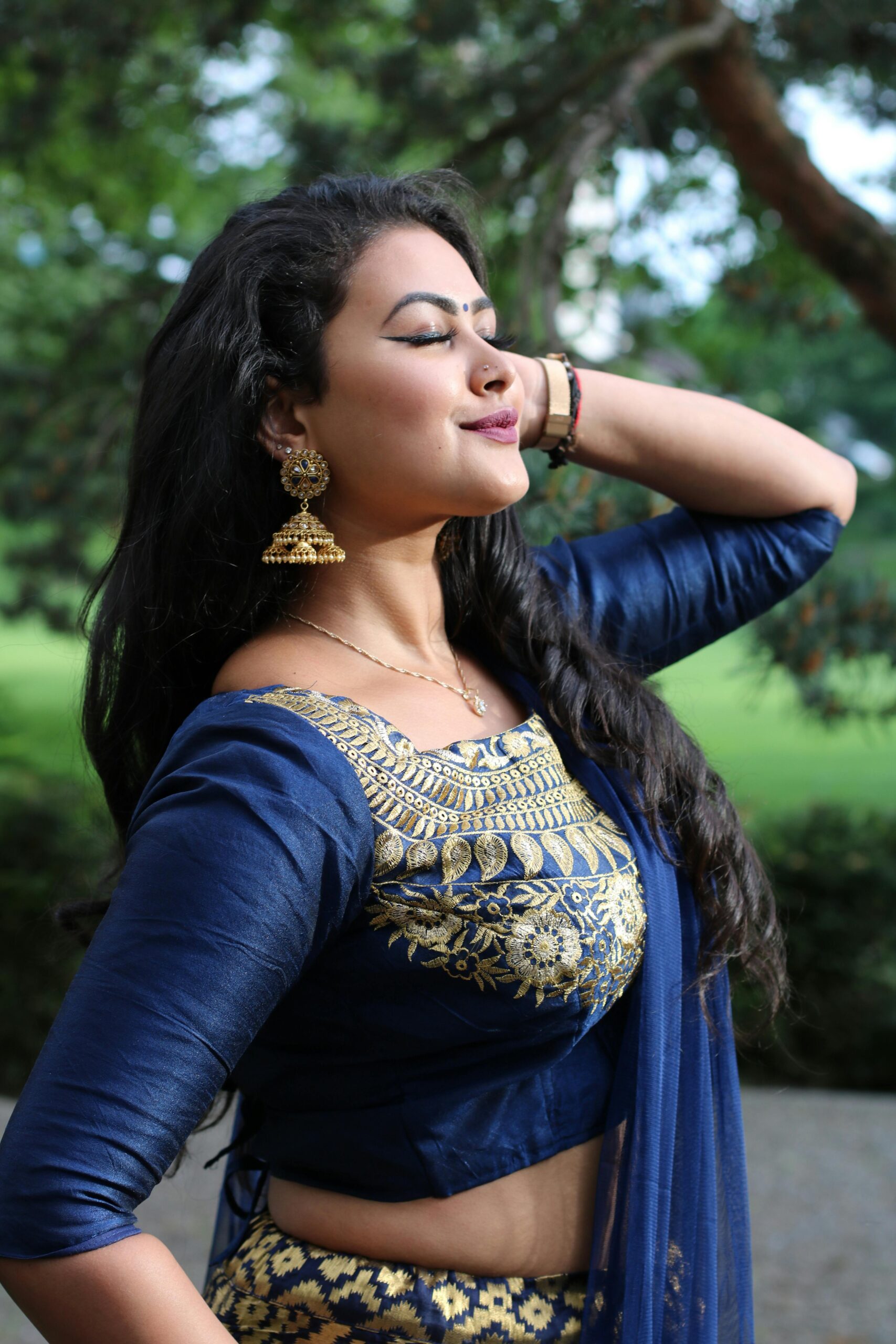 Portrait of a woman in traditional blue and gold attire, posing outdoors.